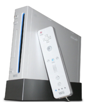 Une console de jeux vidéo Wii, dressée à la verticale sur un socle. Une Wiimote, contrôleur de jeu semblable à une télécommande, est posée contre la console.