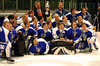 Photo de l'équipe féminine finlandaise qui pose avec un trophée dans la main de son entraîneur.