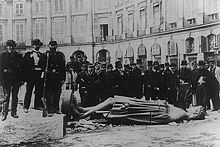 Un groupe de membres de la Commune, à leurs pieds une statue couchée sur le sol
