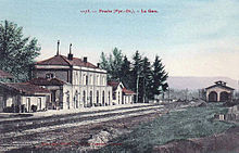 Carte postale colorisé de l'intérieur de la gare, avec les voies, les quais, le bâtiment voyageurs et la remise à locomotives