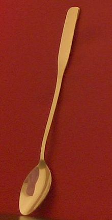 Photographie représentant une cuillère à thé glacé dont le manche est en appui sur un support vertical