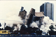  Sur cette image, le Bâtiment fédéral Alfred P.Murrah en pleine démolition. Un camion Ryder peut être vu dans le coin gauche de la photo, et les Regency Towers sont en arrière-plan à droite de l'image. La démolition du bâtiment a créé de grands nuages de poussière qui prennent une bonne partie de l'image.