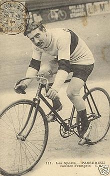 A postcard of a man on a bicycle looking at the camera.