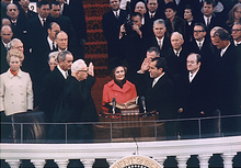 Richard Nixon prêtant serment, assisté de sa femme, autour d'une assemblée assise sur des gradins.
