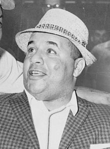 Photographie en noir et blanc d'un gros plan du visage de Roy Campanella portant une sorte de chapeau de paille.