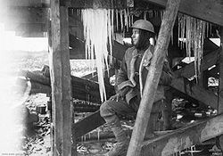 Un militaire se tenant sous une structure en bois
