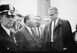Photographie en noir et blanc en extérieur de Martin Luther King et Malcolm X