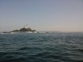L'îlot et le phare de Tevennec par mer calme. On aperçoit au loin la Pointe du Raz et le Phare de la Vieille