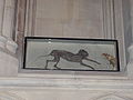Une vitre présente un chat poursuivant une souris, momifiés.