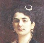 Portrait de Marie Kann, visage de face avec épingle à cheveux en forme de croissant et deux boucles d'oreilles.