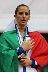 La karatéka italienne Sara Battaglia avec sa médaille d'or autour du cou et un drapeau italien sur les épaules après sa victoire en kata individuel féminin aux championnats du monde de karaté 2006, organisés à Tampere, en Finlande.