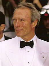 Photographie de Clint Eastwood au Festival de Cannes en 1994. Il est vêtu d'un costume blanc et d'un nœud papillon ; il sourit légèrement, regardant sur le côté