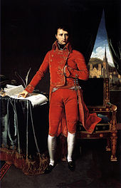   Napoléon debout vu de face, habillé de rouge. Une main glissé dans son habit, il indique des feuilles sur une table