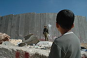 Boy and soldier in front of Israeli wall.jpg