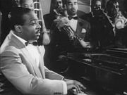 Cropped screenshot of Count Basie from the film Stage Door Canteen.