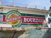 Un mur blanc avec une publicité peinte, reprennant le visuel des étiquettes de bière Bourbon, plus le slogan la dodo lé la