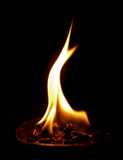 Photographie d'une flamme consumant des copeaux de bois dans une coupelle.