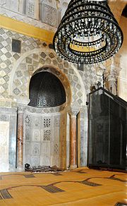 Vue du mihrab revêtu de marbre sculpté et entouré dans sa partie supérieure de carreaux de céramique lustrée.