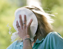 Une femme se faisant écraser une tarte à la crème sur le visage.