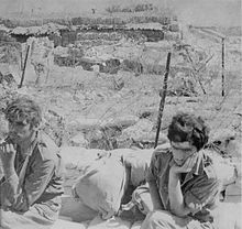 Photographie montrant au premier plan deux prisonniers israéliens assis, l'air abattu.
