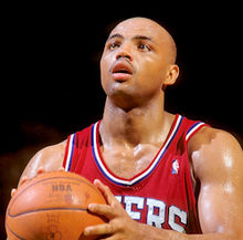 Ballon dans les mains, le joueur de basket-ball Charles Barkley joue sous le maillot rouge des Sixers de Philadelphie.