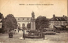 Carte postale ancienne montrant une motrice du Tramway de Troyes derrière le Monument des Enfants de l'Aube, et, en arrière-plan, la Gare