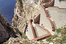 Photographie panoramique des longs escaliers (nommés Escala del Cabirol) pour accéder à la grotte de Neptune