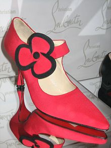 une chaussure rouge, à talon haut, ornée d'une fleur en tissu, créée par Christian Louboutin, exposée au musée Bata de la chaussure