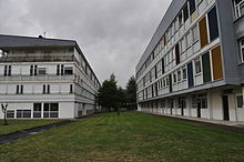 Deux bâtiments imposants encadrent l'image. À droite, le bâtiment Unesco se distingue par ses panneaux colorés, il abrite les enseignements généraux ; à gauche, le bâtiment De Moivre accueille l'internat.