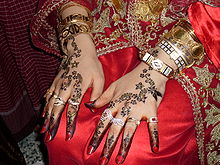 Mariée djerbienne présentant sur ses genoux ses mains couvertes de motifs au henné.