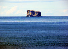 Petite île rocheuse aux falaises abruptes isolée au milieu de l'océan.