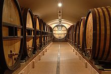 photo récente d'une cave vinicole constituée d'un long et large couloir séparant deux rangées de foudres