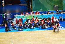 La photographie couleur montre l'équipe alignée entre le parquet de jeu et une longe table où semble siéger des personnalités officielles. Le photographe placé dans les tribunes a donné à son image une plongée qui permet de voir le groupe en entier. Le maillot est rouge et blanc, le bas est bleu.