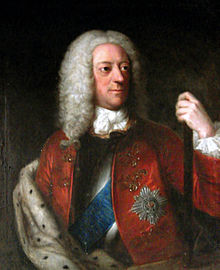 Portrait du haut du corps d'un homme portant une longue perruque. Il porte différents emblèmes sur sa veste d'apparat, et sa main gauche tient une canne.