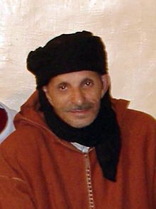 Portrait de Hussein Aït Jimhi en 2007, vêtu d'une djellaba rouge et d'un turban noir