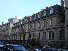 Photographie de la façade principale du lycée Janson-de-Sailly, à Paris, au cours des années 2000 et de la rue passante.