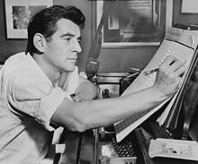 Photographie noir et blanc représentant Leonard Bernstein assis en buste de profil en train d'écrire sur une partition