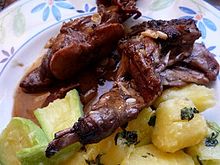La photographie présente une assiette de viande en sauce brune saupoudrée d'ail. Des pommes de terre et des courgettes vapeur sont en accompagnement.