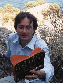 Marc-Édouard Nabe lisant La Peau de Curzio Malaparte devant la villa Malaparte à Capri, en Italie.