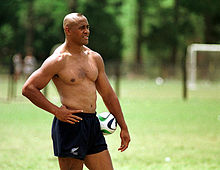 Jonah Lomu torse nu avec un ballon de rugby posé entre son bras gauche et sa hanche