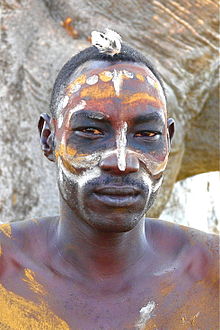 un homme avec le visage peint d'ocres et de blanc