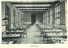 Photographie du réfectoire du lycée : des tables alignées et des chaises.