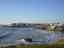 Photographie de la plage du Chay à marée haute montrant les deux anses creusées dans une côte rocheuse, bordée de villas.