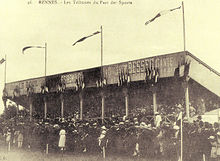 Photographie d'époque montrant la première tribune en bois construite au parc des sports de la route de Lorient en 1912.