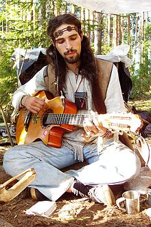 Homme habillé à la façon hippie et jouant de la guitare (photographie)