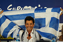 Accéder aux informations sur cette image nommée Sakis Rouvas Raising Greek Flag.jpg.