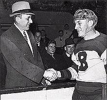 Photo noir et blanc de Eddie Shore, dans la tenue des Bruins, serrant la main de Ace Bailey en tenue civile.