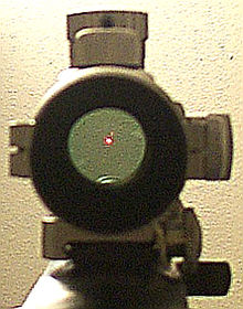 Vue au travers d'un viseur point rouge ProPoint de marque Tasco. L'image dans la lunette donne l'impression qu'un laser rouge est projeté sur le mur.