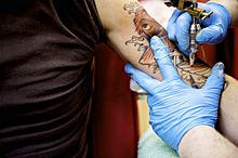 Photo d'une séance de tatouage sur le bras gauche.