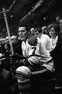 Photo noir et blanc de Tim Horton avec le maillot des Maple Leafs de Toronto assis sur le banc de pénalité durant une rencontre